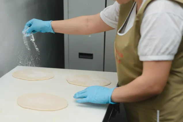 Dusting flour over dough rounds